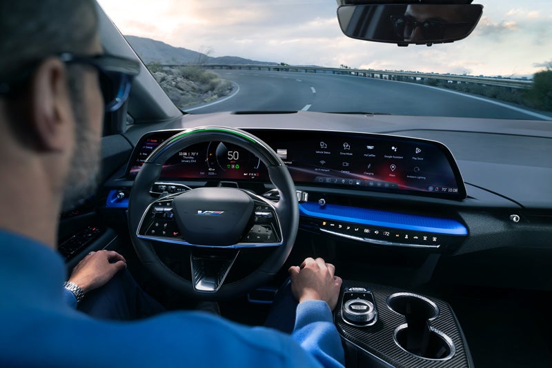 Front View of the 2026 OPTIQ-V Driving Through the Dusk Utilizing its Headlights | ELCO Cadillac in Ballwin MO