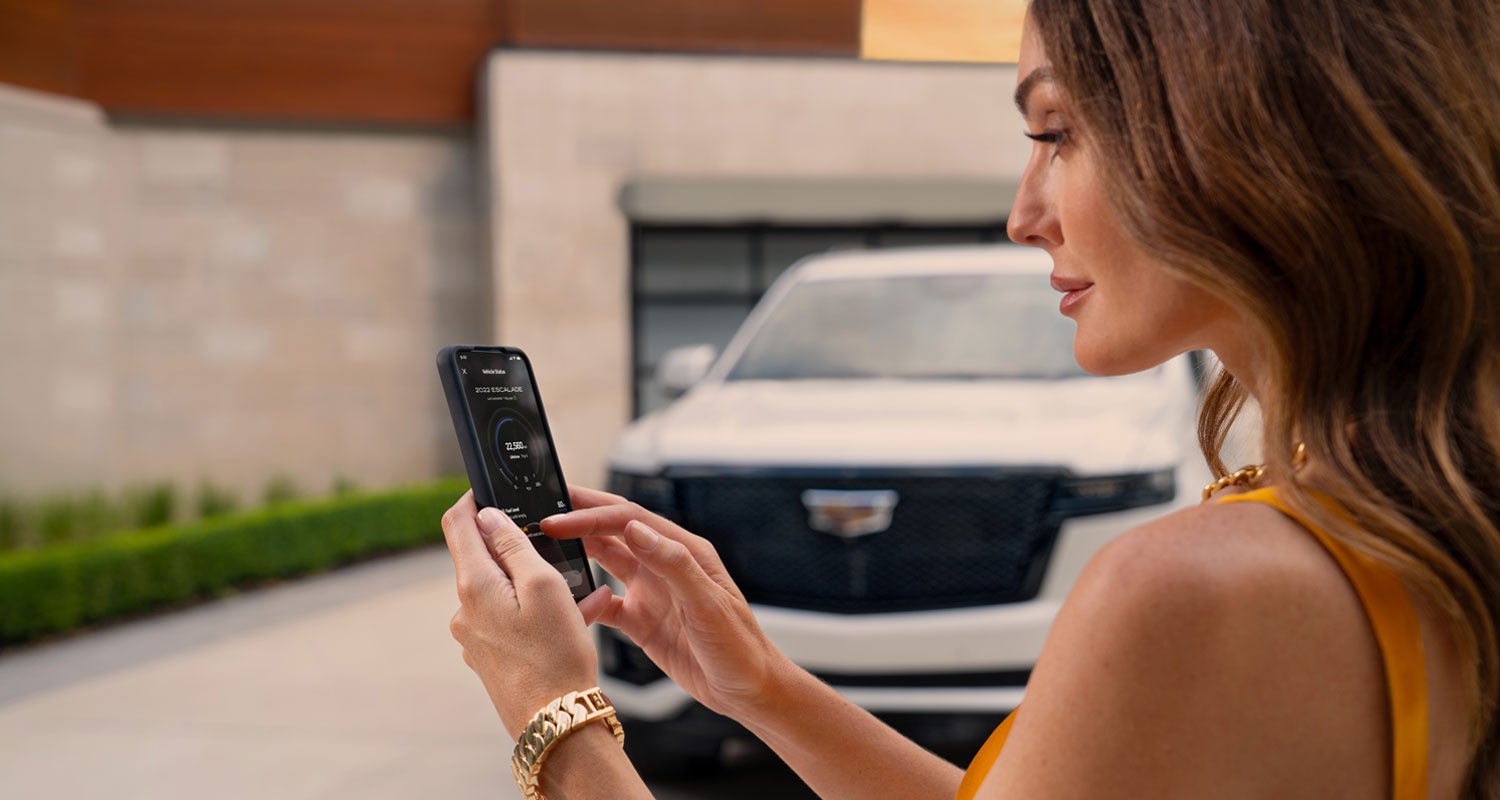 lady checking her mobile with a Cadillac vehicle background | ELCO Cadillac in Ballwin MO