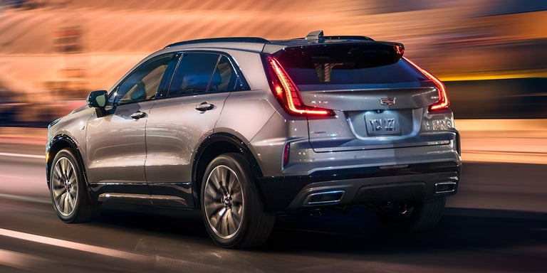 Rear View of the 2025 Cadillac XT4 Driving Fast Through the City at Night